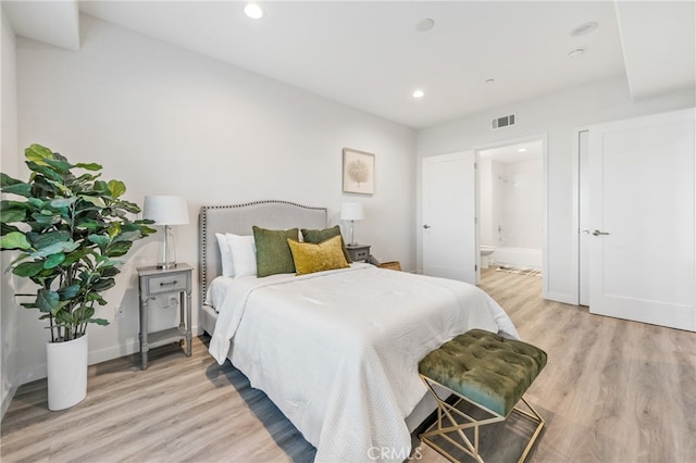 bedroom with light wood-type flooring and ensuite bath