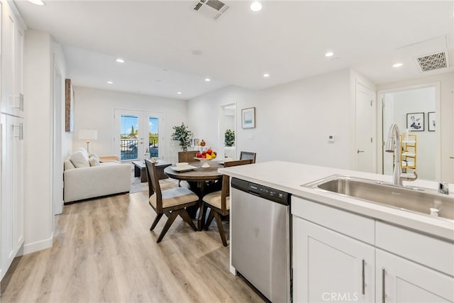 kitchen with white cabinetry, light hardwood / wood-style floors, sink, and stainless steel dishwasher