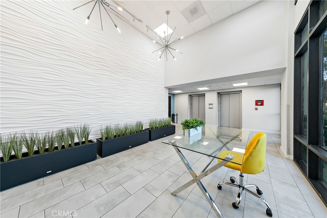 interior space featuring light tile patterned floors, a towering ceiling, elevator, and a notable chandelier