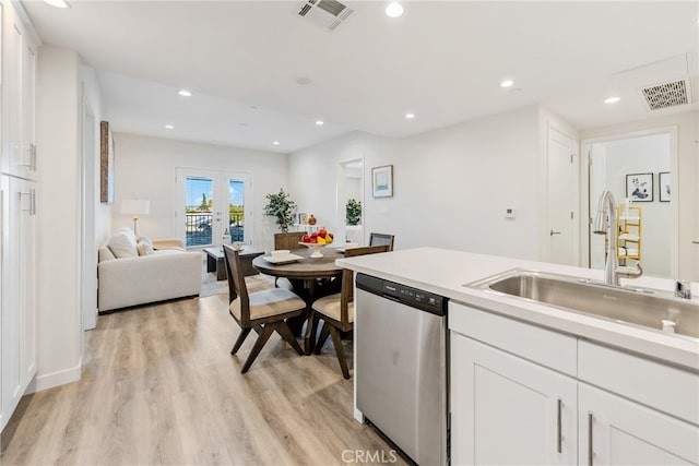 kitchen featuring white cabinets, dishwasher, light wood-type flooring, and sink