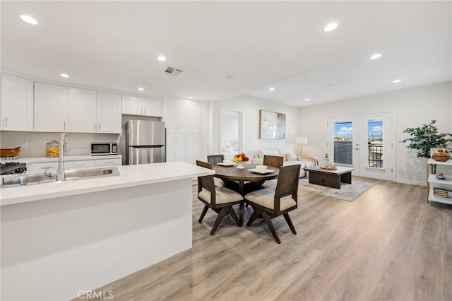 kitchen with appliances with stainless steel finishes, light hardwood / wood-style floors, white cabinetry, and sink