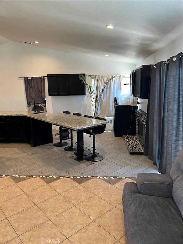 kitchen featuring a textured ceiling, light tile patterned floors, and vaulted ceiling