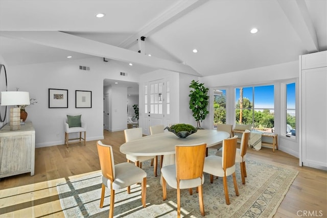 dining room with lofted ceiling with beams and light hardwood / wood-style flooring