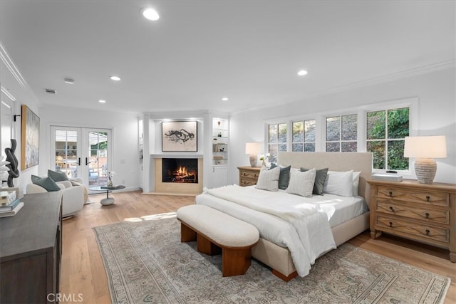 bedroom with crown molding, light hardwood / wood-style flooring, and french doors