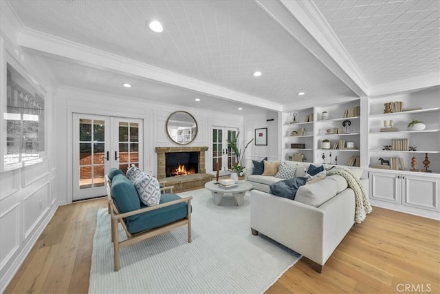 living room with light wood-type flooring, french doors, beam ceiling, ornamental molding, and built in shelves