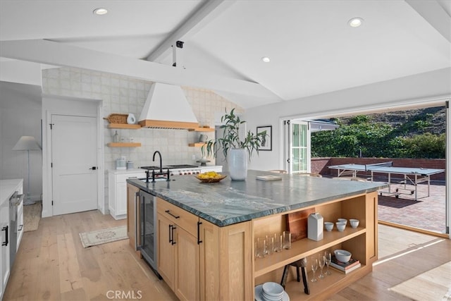 kitchen featuring sink, vaulted ceiling with beams, light hardwood / wood-style floors, wine cooler, and premium range hood