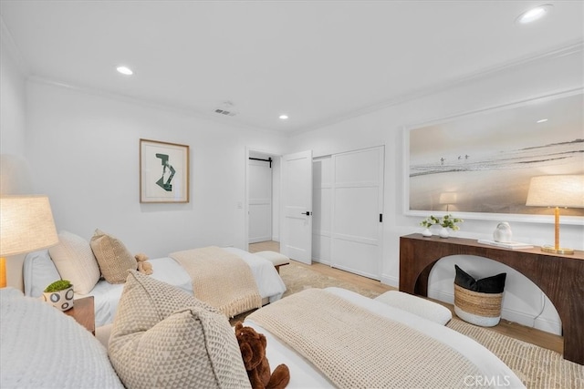 bedroom with a closet, light hardwood / wood-style floors, and ornamental molding