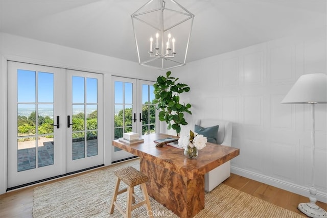 dining space with french doors, a notable chandelier, and light wood-type flooring