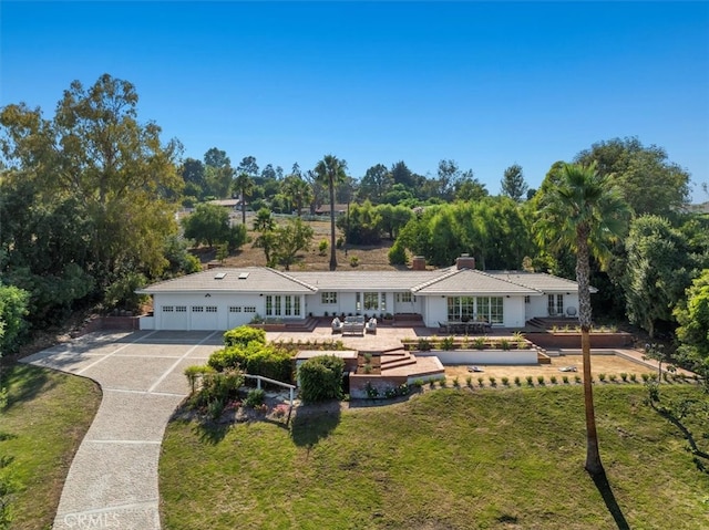 ranch-style home featuring a garage and a front lawn