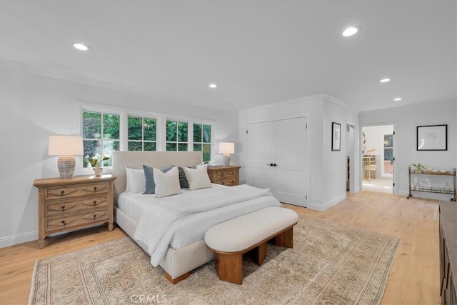 bedroom featuring light hardwood / wood-style floors, crown molding, and a closet