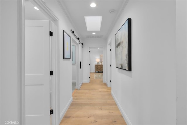 hallway featuring crown molding, a barn door, and light hardwood / wood-style floors