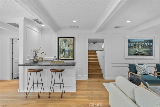 kitchen with a kitchen breakfast bar, ornamental molding, and light wood-type flooring