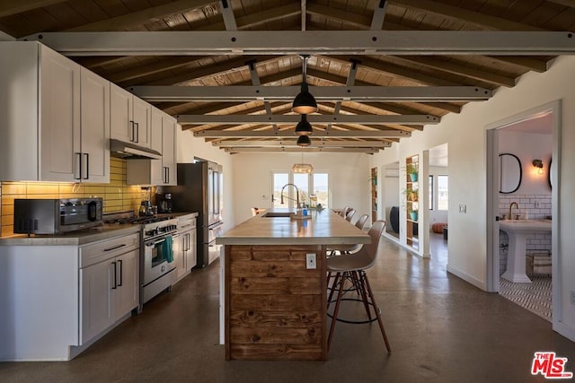 kitchen featuring an island with sink, white cabinetry, sink, backsplash, and stainless steel appliances