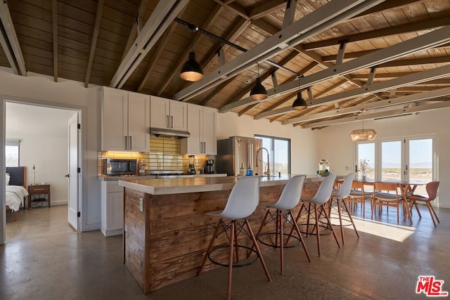 kitchen featuring a kitchen island with sink, high end fridge, white cabinets, and wood ceiling