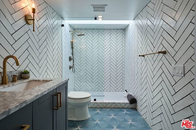 bathroom featuring vanity, tiled shower, and toilet