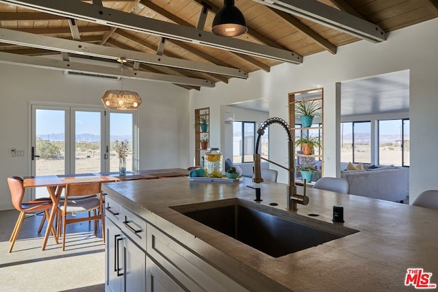 kitchen with sink, hanging light fixtures, vaulted ceiling with beams, a mountain view, and wooden ceiling