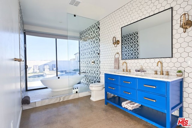 bathroom with vanity, a tub to relax in, concrete flooring, and tile walls