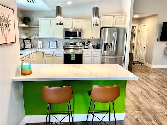 kitchen featuring pendant lighting, stainless steel appliances, white cabinets, and a breakfast bar