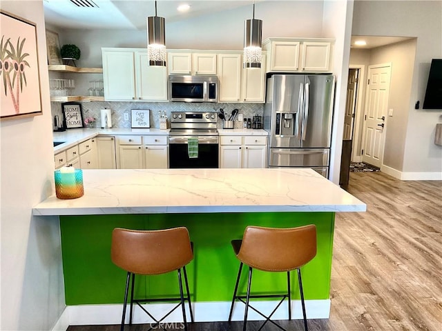 kitchen with a kitchen bar, stainless steel appliances, open shelves, and baseboards