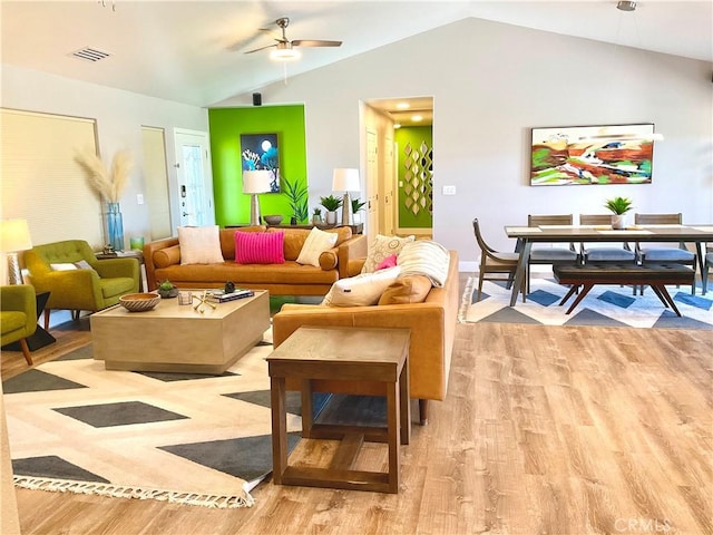 living area featuring a ceiling fan, visible vents, lofted ceiling, and light wood-type flooring