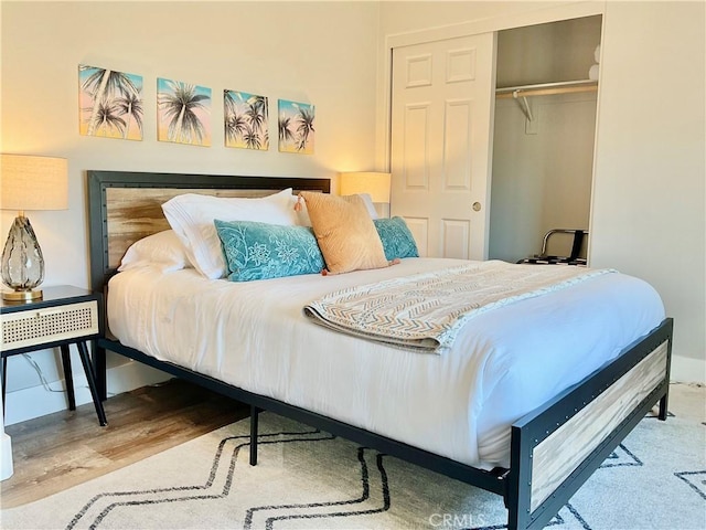bedroom featuring baseboards, wood finished floors, and a closet