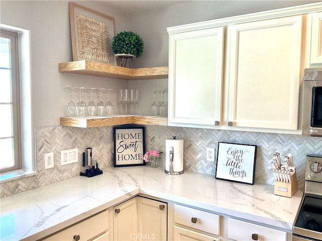 kitchen with appliances with stainless steel finishes, tasteful backsplash, light stone counters, and plenty of natural light