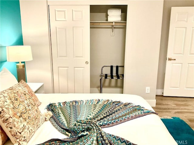 bedroom with wood finished floors and a closet