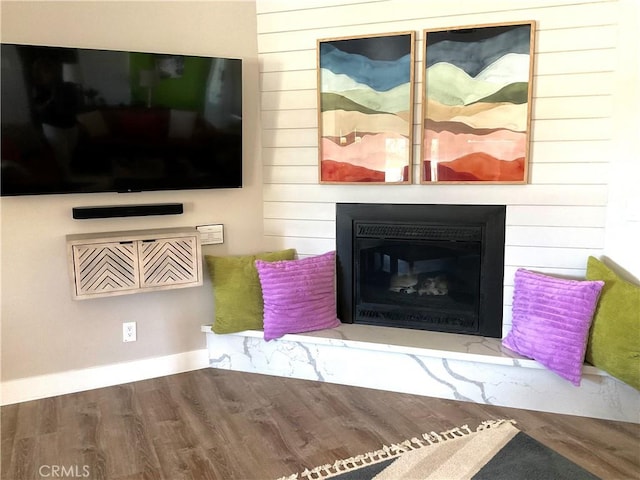 living area with wood walls, a glass covered fireplace, and wood finished floors