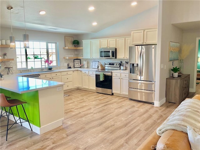kitchen with a sink, open shelves, a breakfast bar area, a peninsula, and appliances with stainless steel finishes