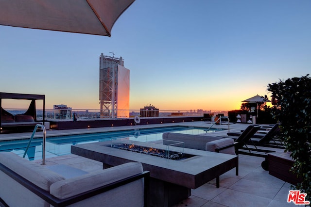 pool at dusk with a fire pit and a patio