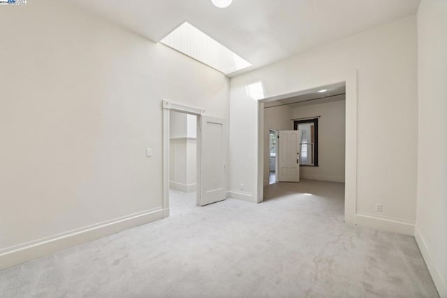 unfurnished room featuring a skylight and light carpet