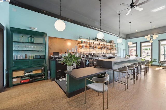 bar with pendant lighting, green cabinets, and ceiling fan