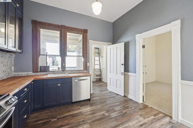 kitchen featuring butcher block countertops, dark hardwood / wood-style flooring, blue cabinetry, appliances with stainless steel finishes, and sink