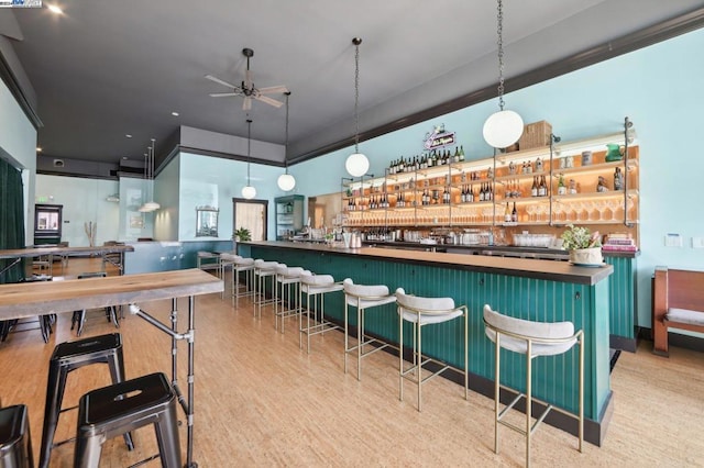 bar with hanging light fixtures, ceiling fan, and light hardwood / wood-style floors