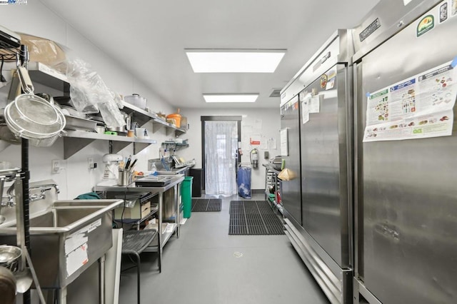 interior space with concrete flooring, built in refrigerator, and sink