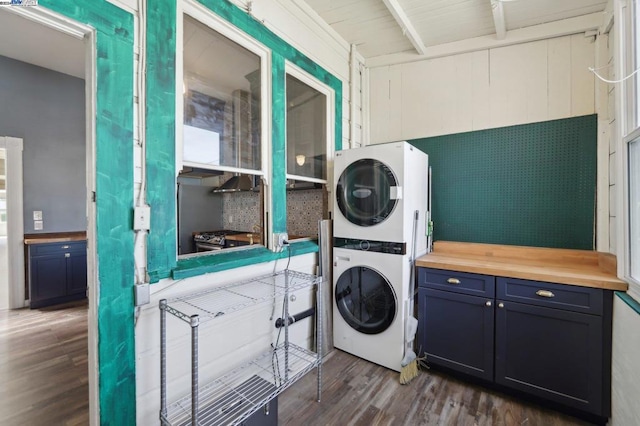 laundry room with hardwood / wood-style floors and stacked washer / drying machine