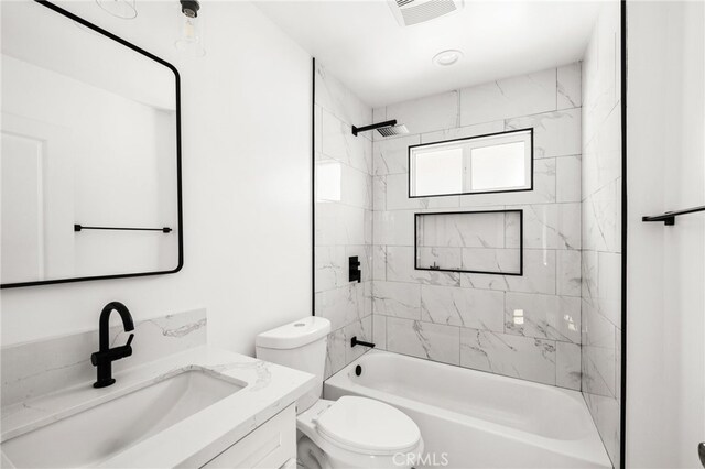 full bathroom with tiled shower / bath combo, vanity, and toilet