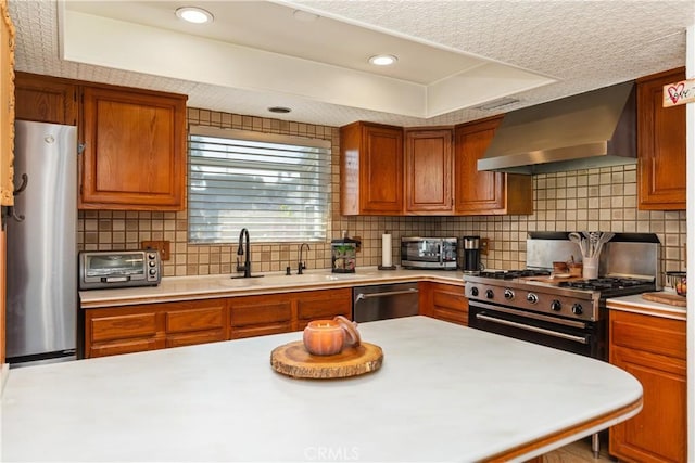 kitchen featuring decorative backsplash, a textured ceiling, stainless steel appliances, sink, and wall chimney range hood