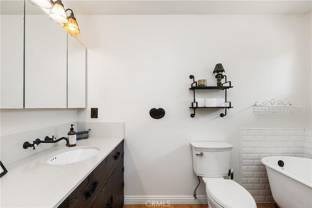 bathroom featuring a washtub, vanity, and toilet