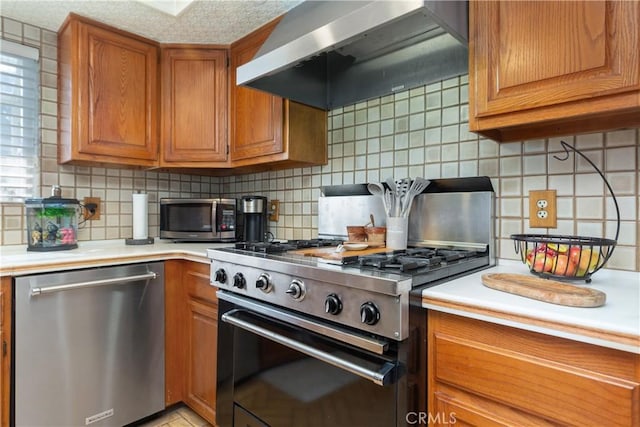 kitchen with backsplash, wall chimney exhaust hood, stainless steel appliances, and a textured ceiling