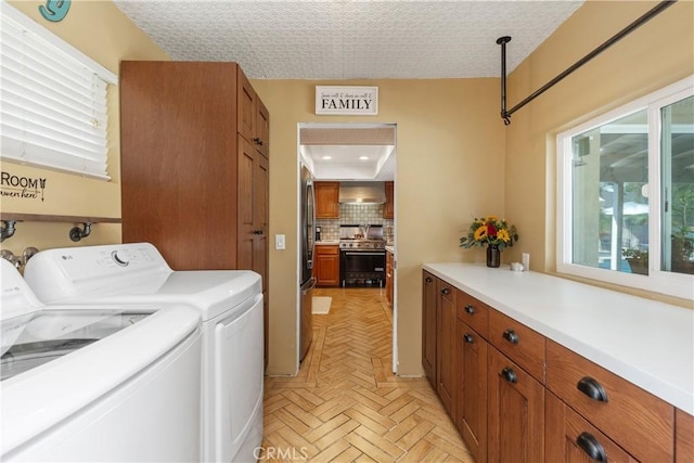 laundry room with light parquet flooring, cabinets, a textured ceiling, and washing machine and clothes dryer