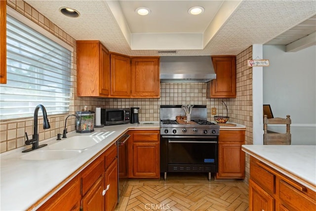 kitchen with light parquet floors, sink, wall chimney exhaust hood, decorative backsplash, and stainless steel appliances