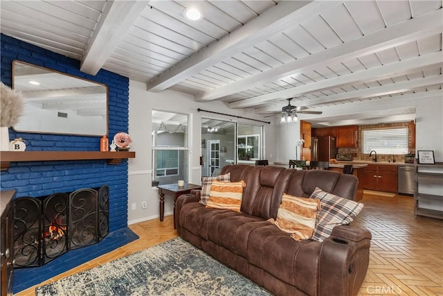 living room with a brick fireplace, light parquet floors, ceiling fan, wooden ceiling, and beamed ceiling