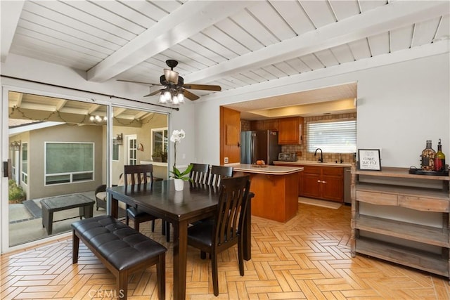 dining room with ceiling fan, beam ceiling, sink, and light parquet floors