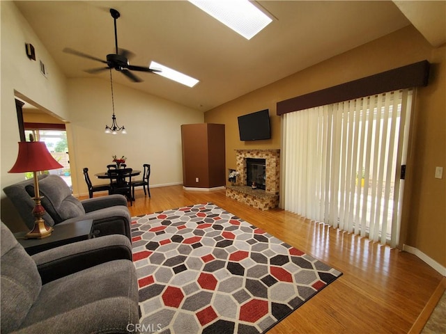 living room with ceiling fan, a fireplace, light hardwood / wood-style flooring, and vaulted ceiling