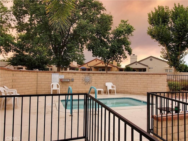 pool at dusk featuring a patio area