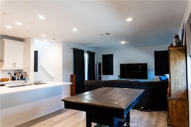 kitchen featuring decorative backsplash, light hardwood / wood-style floors, white cabinetry, and sink