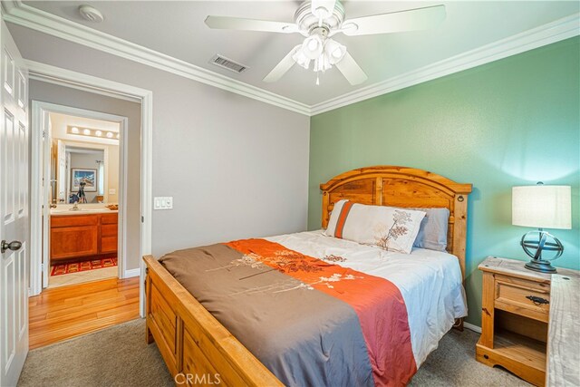 bedroom featuring ornamental molding, dark carpet, ensuite bath, and ceiling fan