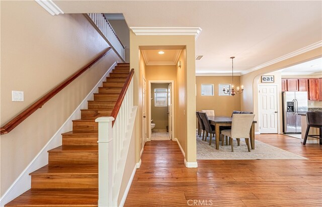 stairs featuring ornamental molding, hardwood / wood-style floors, and a chandelier