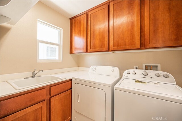 washroom featuring washing machine and clothes dryer, cabinets, and sink